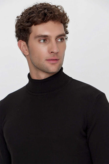Man wearing a basic black turtleneck sweater with a relaxed fit, plain background