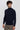 Man wearing a slim-fit black turtleneck sweater and beige trousers on plain background