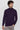Man wearing a dark purple turtleneck sweater and light grey pants against a plain background