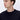 Man wearing a black crew neck sweater, relaxed fit, looking left, on white background