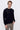 Man wearing a black long sleeve crew neck sweater and beige pants against white background