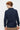 Back view of man wearing navy long sleeve polo shirt and beige trousers