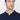 Man wearing a navy blue polo shirt with button placket, relaxed fit, on white background