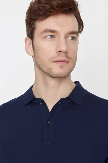 Man wearing a navy blue polo shirt with button placket, relaxed fit, on white background