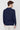 Back view of man wearing a navy blue long sleeve polo shirt with white trousers