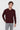 Man wearing burgundy long sleeve polo shirt and light grey jeans on white background