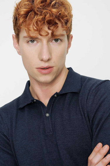 Man wearing a navy blue relaxed fit polo shirt with buttoned collar, casual fashion style