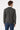 Man wearing grey long-sleeve sweater and blue jeans, back view, casual outfit