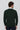 Back view of man wearing a dark green long sleeve V-neck sweater with white shirt