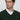 Man wearing a dark green V-neck sweater over a white dress shirt, relaxed fit.