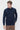 Man wearing a navy blue crew neck sweater and brown trousers on white background