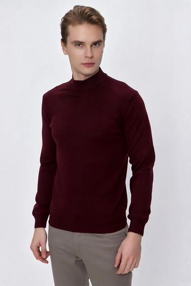 Man wearing a burgundy long sleeve mock neck sweater and light grey trousers