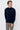 Man wearing a navy blue mock neck sweater and beige trousers against a plain background