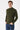 Man wearing an olive green turtleneck sweater and blue jeans on a white background