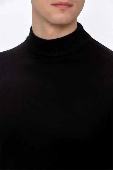 Close-up of a man wearing a black mock neck sweater, relaxed fit, plain background