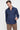 Man wearing a navy blue slim fit dress shirt and brown trousers on a plain background