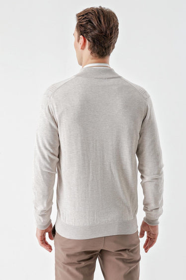 Back view of a man wearing a beige jacquard knit zip sweater and taupe trousers