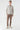 Man wearing a beige zip-up jacquard sweater, brown pants, and casual sneakers