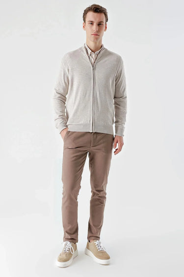 Man wearing a beige zip-up jacquard sweater, brown pants, and casual sneakers