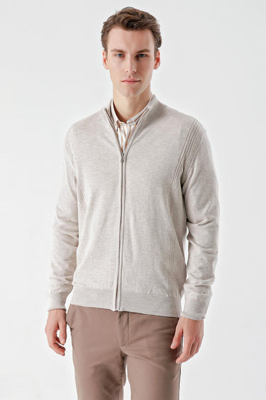 Man wearing a beige zip-up knit jacket with subtle jacquard detailing and brown trousers