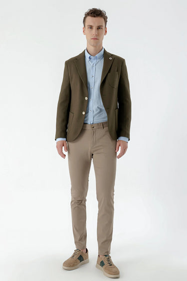 Man wearing olive green slim fit blazer, light blue shirt, beige slim trousers and sneakers