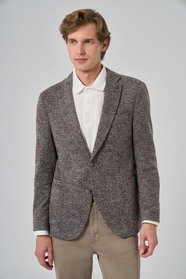 Man wearing a brown checkered knit blazer with white shirt and beige trousers