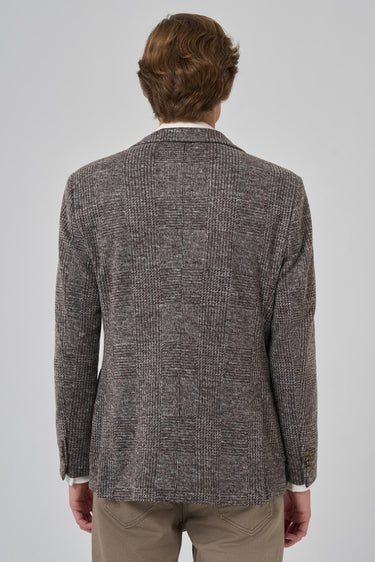 Back view of a man wearing a brown checked knit blazer and beige trousers