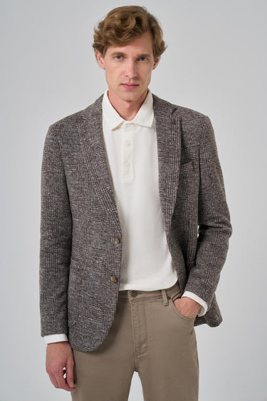 Man wearing a brown checkered knit blazer with beige pants and a white collared shirt