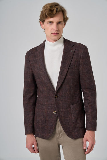 Man wearing a brown checked blazer over a white turtleneck and beige trousers