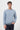 Man wearing a light blue crew neck sweatshirt and dark trousers, front view on white background.