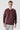 Man wearing a plain burgundy crew neck sweatshirt and light gray pants on white background