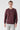 Man wearing a plain burgundy crew neck sweatshirt and light gray jeans on white background