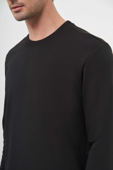 Close-up of man wearing a black crew neck long sleeve t-shirt, minimalist style
