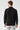 Man wearing black basic half turtleneck sweater, back view, with light grey jeans