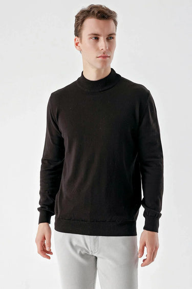 Man wearing a black basic half turtleneck sweater with long sleeves, light jeans, studio setting