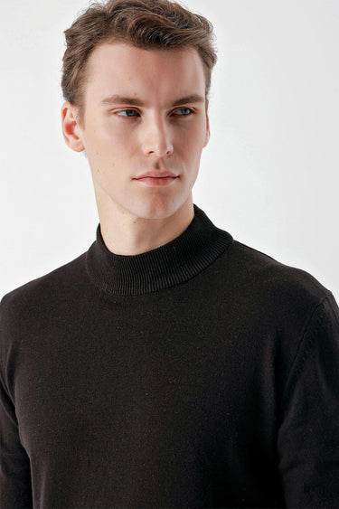 Man wearing a black basic half turtleneck sweater against a light background