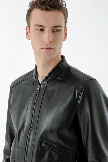Man wearing a black faux leather zip-up jacket with side pockets, modern fashion style