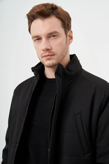 Man wearing a black snap-button jacket with high collar, stylish modern outerwear