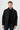 Man wearing a black snap-button jacket with high collar and front pockets, fashion photo