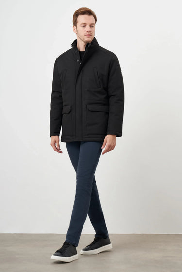 Man wearing a black snap-button jacket with pockets and navy trousers, casual look