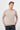 Man wearing a light beige crew neck sweatshirt and dark jeans on white background