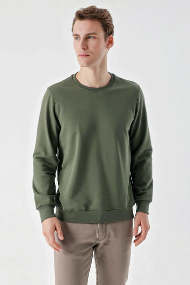 Man wearing a green crew neck long sleeve sweatshirt with beige trousers