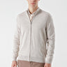 Man wearing a beige zip-up knit jacket with subtle jacquard detailing and brown trousers
