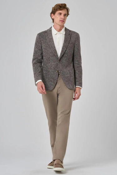 Man wearing brown plaid knit blazer, white shirt, beige trousers, and loafers