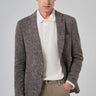 Man wearing a brown checkered knit blazer with beige pants and a white collared shirt
