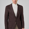 Man wearing brown checkered knit blazer, white turtleneck, and beige pants
