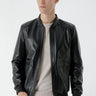 Man wearing black faux leather bomber jacket with zip front and ribbed cuffs