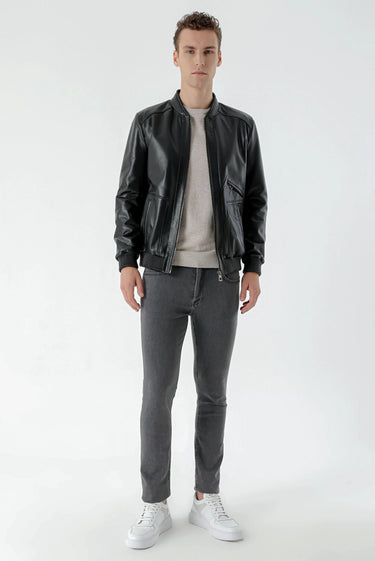 Man wearing black leather jacket, grey slim-fit jeans, white sneakers, light sweater