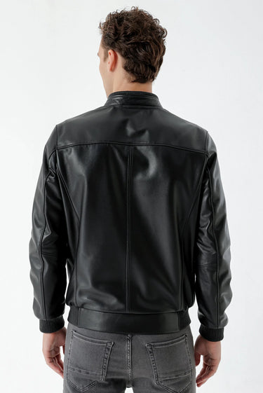 Man wearing a black faux leather jacket and grey jeans, back view
