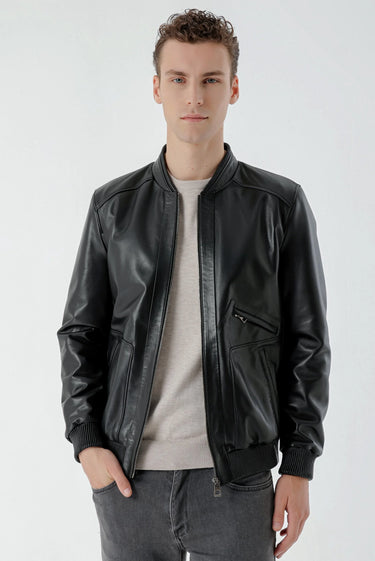 Man wearing black faux leather bomber jacket with zip details and grey jeans on white background